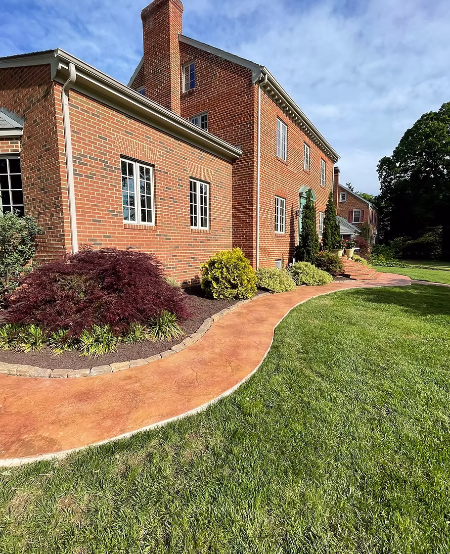 Curved stamped-concrete walkway and foundation planting at a Richmond, VA home by Montgomery Landscape